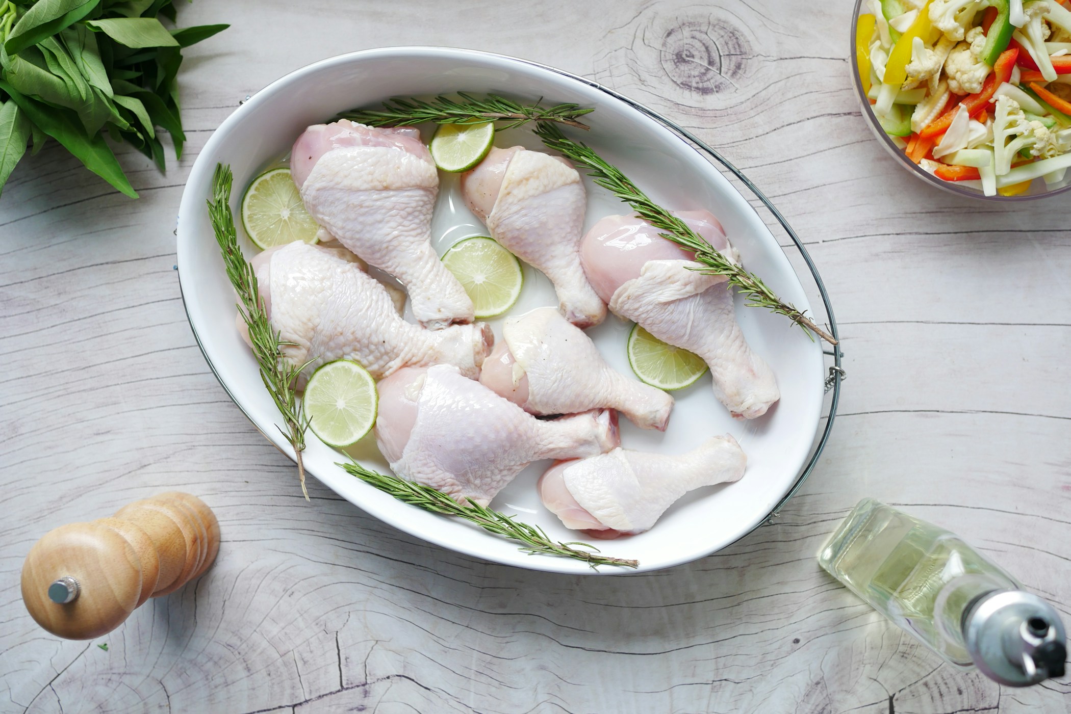 Raw chicken drumstick in a bowl on the table.